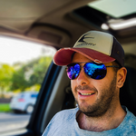 Fisherman wearing a pair of MAHI Fishing Sunglasses - Dark Gun Blue Mirror while sitting in his car